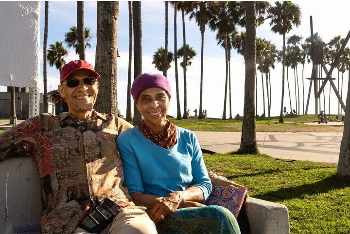 Young couple sitting close together on a bench at the beach at golden hour