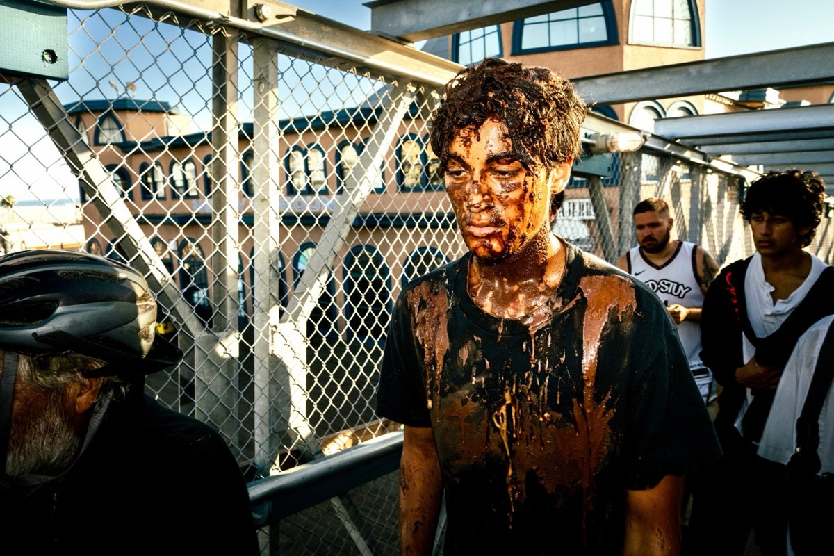 Young man covered in chocolate walking across the Santa Monica pier bridge