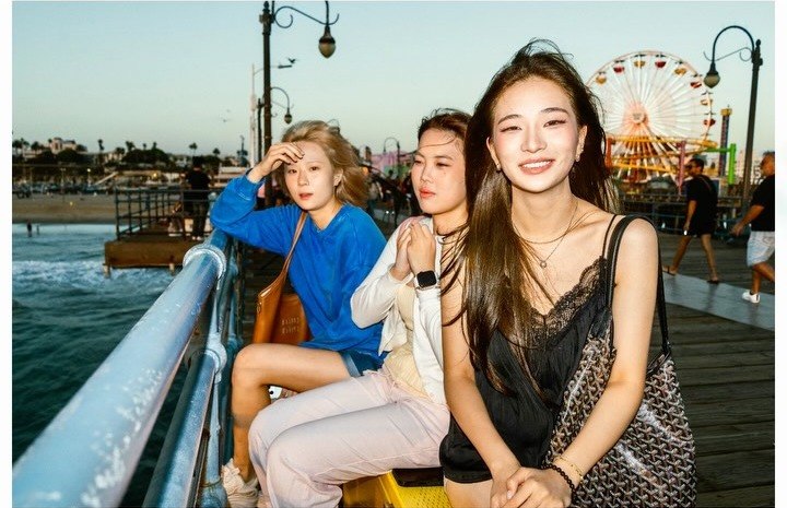Three friends posing together on Santa Monica Pier at golden hour
